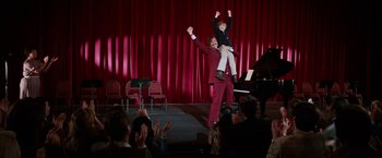 Movie still from “Anchorman 2: The Legend Continues” (2013), directed by Adam McKay – A man and a child are on stage with a crowd; Wide shot, High angle
