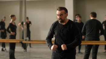 Movie still from “And Then We Danced” (2019), directed by Levan Akin – A man in a black shirt is standing in a room; Medium shot, Low angle