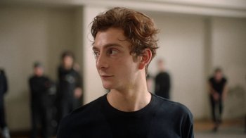 Movie still from “And Then We Danced” (2019), directed by Levan Akin – A young man in a black t - shirt looking to his left; Close Up shot, Low angle