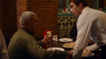 Movie still from “And Then We Danced” (2019), directed by Levan Akin – Two men sitting at a table with plates of food in front of them; Medium shot, Over the shoulder angle