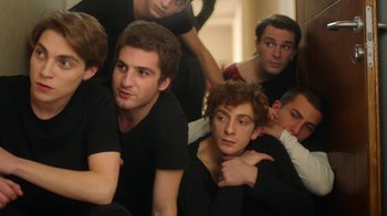 Movie still from “And Then We Danced” (2019), directed by Levan Akin – A group of young men sitting next to each other; Medium shot, High angle
