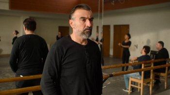 Movie still from “And Then We Danced” (2019), directed by Levan Akin – A man in a black shirt standing in front of a group of people; Medium shot, Low angle