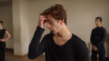 Movie still from “And Then We Danced” (2019), directed by Levan Akin – A young man in a black shirt is holding his hand up to his head; Close Up shot, Over the shoulder angle