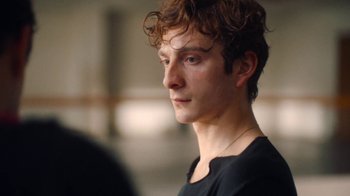 Movie still from “And Then We Danced” (2019), directed by Levan Akin – A man with curly red hair wearing a black t - shirt; Close Up shot, Over the shoulder angle