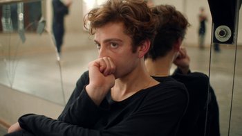 Movie still from “And Then We Danced” (2019), directed by Levan Akin – A young man sitting in front of a mirror with his hand under his chin; Close Up shot, Over the shoulder angle