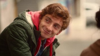Movie still from “And Then We Danced” (2019), directed by Levan Akin – A young man smiling for the camera while wearing a green jacket; Close Up shot, Low angle