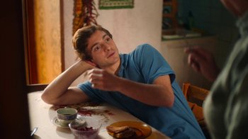 Movie still from “And Then We Danced” (2019), directed by Levan Akin – A man sitting at a table with a bowl of food; Medium shot, Over the shoulder angle