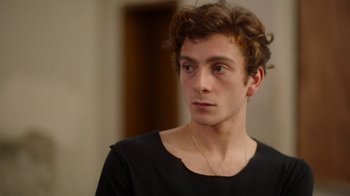 Movie still from “And Then We Danced” (2019), directed by Levan Akin – A young man wearing a black t - shirt looks to his left; Close Up shot, Over the shoulder angle