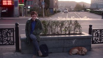 Movie still from “And Then We Danced” (2019), directed by Levan Akin – A person sitting on a ledge smoking a cigarette; Medium shot, Over the shoulder angle
