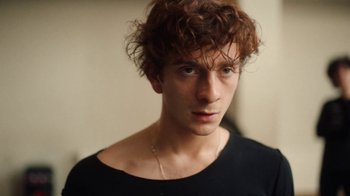 Movie still from “And Then We Danced” (2019), directed by Levan Akin – A person wearing a black shirt; Close Up shot, Over the shoulder angle