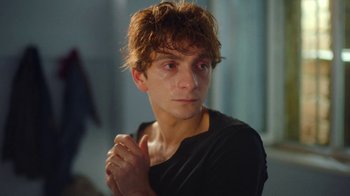 Movie still from “And Then We Danced” (2019), directed by Levan Akin – A young man with red curly hair and a black shirt; Close Up shot, Over the shoulder angle