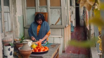 Movie still from “And Then We Danced” (2019), directed by Levan Akin – A woman sitting at a table cutting up tomatoes; Medium shot, High angle