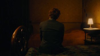 Movie still from “And Then We Danced” (2019), directed by Levan Akin – A person sitting on a bed in a room; Medium shot, High angle