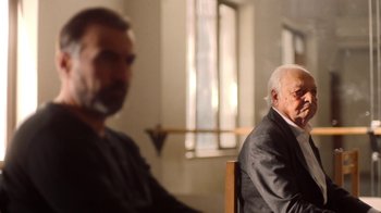 Movie still from “And Then We Danced” (2019), directed by Levan Akin – Two older men sitting in a room next to each other; Medium shot, Over the shoulder angle