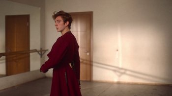 Movie still from “And Then We Danced” (2019), directed by Levan Akin – A man in a red robe standing next to a door; Medium shot, Low angle