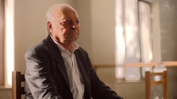 Movie still from “And Then We Danced” (2019), directed by Levan Akin – An old man in a suit sitting in front of a window; Close Up shot, Low angle