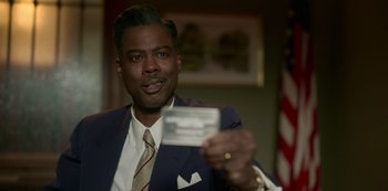 Movie still from “Fargo” (2014), created by Noah Hawley – A man in a suit and tie holding a business card; Close Up shot, Over the shoulder angle