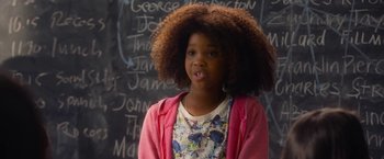 Movie still from “Annie” (2014), directed by Will Gluck – A young girl standing in front of a blackboard; Close Up shot, Over the shoulder angle