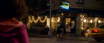 Movie still from “Annie” (2014), directed by Will Gluck – A couple of people that are standing on the side of the street; Wide shot, Over the shoulder angle
