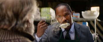 Movie still from “Annie” (2014), directed by Will Gluck – A man in a suit and tie holding a fork with a piece of cake in it; Close Up shot, Over the shoulder angle