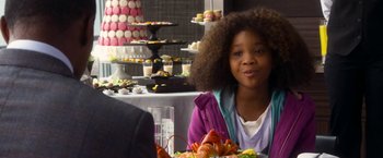 Movie still from “Annie” (2014), directed by Will Gluck – A woman sitting in front of a table with a plate of food; Close Up shot, Over the shoulder angle