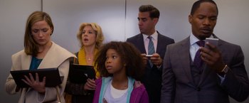 Movie still from “Annie” (2014), directed by Will Gluck – A group of people standing next to each other in a room; Medium shot, Over the shoulder angle