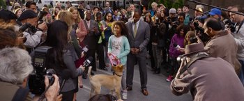 Movie still from “Annie” (2014), directed by Will Gluck – A crowd of people standing around a brown dog; Wide shot, Over the shoulder angle
