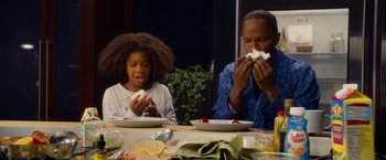 Movie still from “Annie” (2014), directed by Will Gluck – Two people sitting at a table eating food; Medium shot, Over the shoulder angle