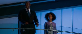 Movie still from “Annie” (2014), directed by Will Gluck – A man in a suit stands next to a young girl; Medium shot, Low angle