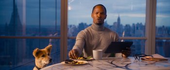 Movie still from “Annie” (2014), directed by Will Gluck – A man sitting at a table with food in front of him; Medium shot, Over the shoulder angle