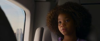 Movie still from “Annie” (2014), directed by Will Gluck – A little girl sitting in a car seat looking into the camera; Close Up shot, Over the shoulder angle