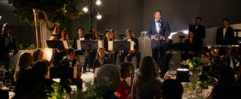 Movie still from “Annie” (2014), directed by Will Gluck – A group of people sitting in a room with musical instruments; Wide shot, Over the shoulder angle