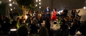 Movie still from “Annie” (2014), directed by Will Gluck – A man and a woman sing at an orchestra; Extreme Wide shot, Over the shoulder angle