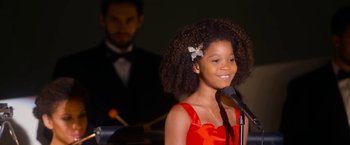 Movie still from “Annie” (2014), directed by Will Gluck – A girl in a red dress is speaking into a microphone; Close Up shot, Low angle
