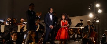 Movie still from “Annie” (2014), directed by Will Gluck – A man and a woman standing next to each other on a stage; Medium shot, Over the shoulder angle