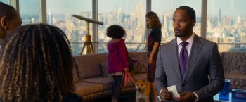 Movie still from “Annie” (2014), directed by Will Gluck – A group of people and a dog in front of a large window; Medium shot, Over the shoulder angle