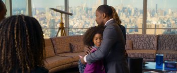 Movie still from “Annie” (2014), directed by Will Gluck – A man and a little girl hugging in a living room; Medium shot, Over the shoulder angle