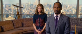 Movie still from “Annie” (2014), directed by Will Gluck – A man and a woman standing next to each other in front of a window; Medium shot, Over the shoulder angle