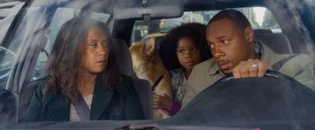 Movie still from “Annie” (2014), directed by Will Gluck – Two people and a dog in the back of a car; Medium shot, Over the shoulder angle