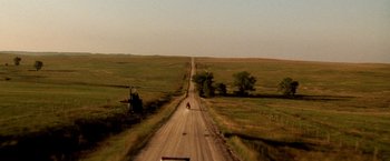 Movie still from “Armageddon” (1998), directed by Michael Bay – A dirt road that has a tractor on the side of it; Extreme Wide shot, High angle