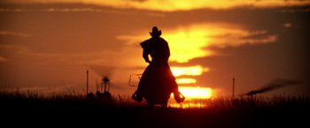 Movie still from “Armageddon” (1998), directed by Michael Bay – A man riding on the back of a horse at sunset; Wide shot, Low angle