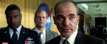 Movie still from “Armageddon” (1998), directed by Michael Bay – A man in a suit and tie standing next to another man in a suit and tie; Close Up shot, Low angle