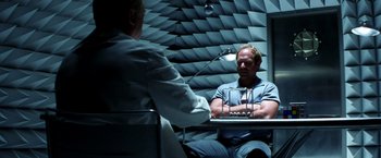 Movie still from “Armageddon” (1998), directed by Michael Bay – Two men are sitting in front of each other in an anechoic chamber; Medium shot, Over the shoulder angle