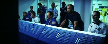Movie still from “Armageddon” (1998), directed by Michael Bay – A group of men in blue shirts and ties sitting next to each other in a room; Medium shot, Low angle