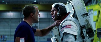 Movie still from “Armageddon” (1998), directed by Michael Bay – A man is putting a helmet on another man's head; Medium shot, Over the shoulder angle