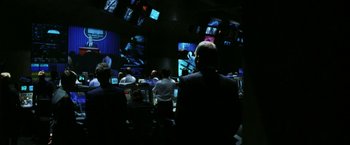 Movie still from “Armageddon” (1998), directed by Michael Bay – A group of people sitting in a dark room; Wide shot, Over the shoulder angle