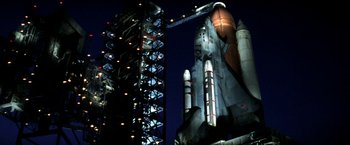 Movie still from “Armageddon” (1998), directed by Michael Bay – A space shuttle on display at night with a tower in the background; Extreme Wide shot, Low angle