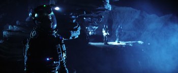 Movie still from “Armageddon” (1998), directed by Michael Bay – Two people in a dark room with a space suit on; Wide shot, Low angle