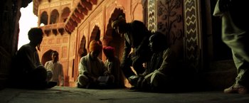 Movie still from “Armageddon” (1998), directed by Michael Bay – A group of men sitting on the ground in front of a building; Wide shot, Low angle