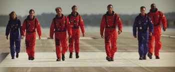 Movie still from “Armageddon” (1998), directed by Michael Bay – A group of men in orange suits walking on a runway; Medium shot, Low angle